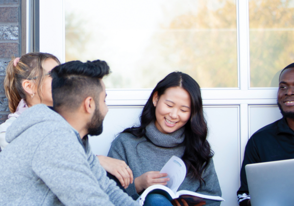 Male and female students hanging out together outside a building